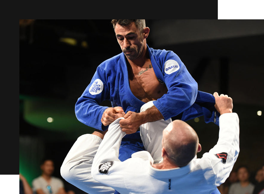 Brazilian Jiu Jitsu athletes in action during a BJJ match, showcasing a blue Braus Fight gi against a white gi, emphasizing technique and dynamic movement.