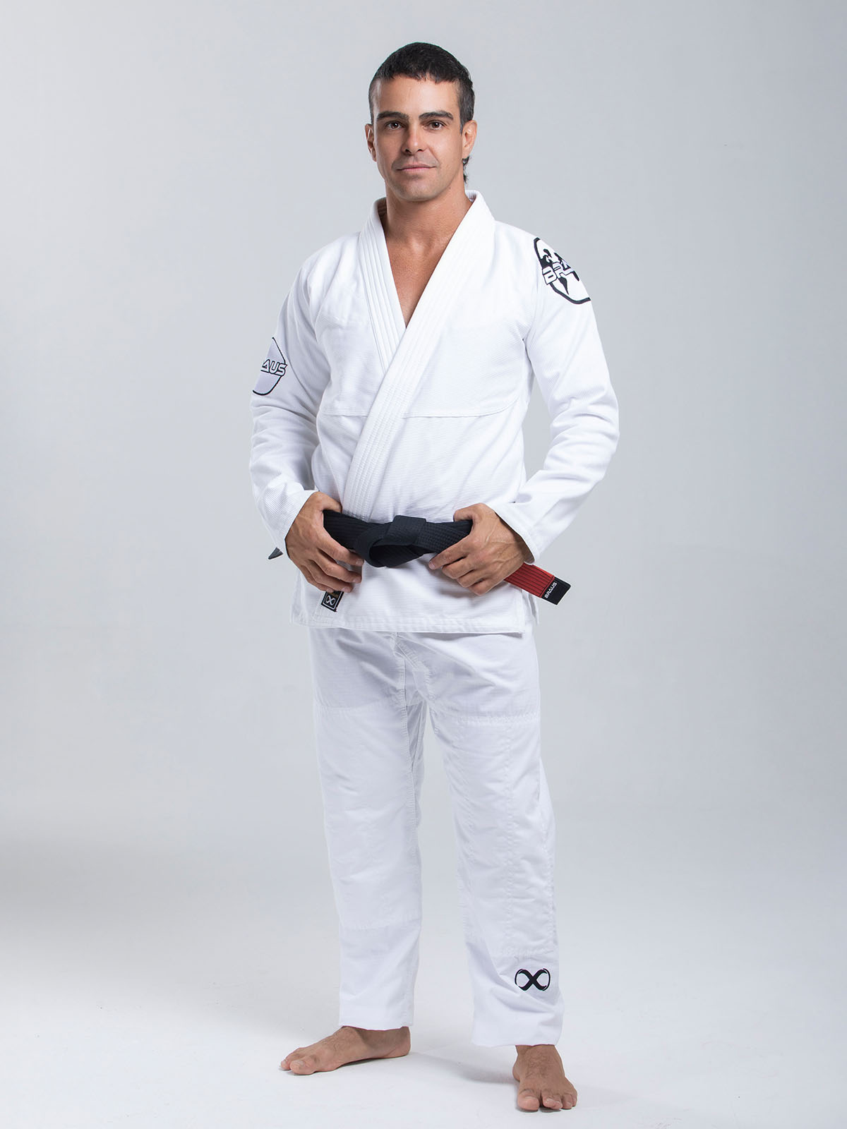 Man wearing a white martial arts uniform with a belt on a gray background