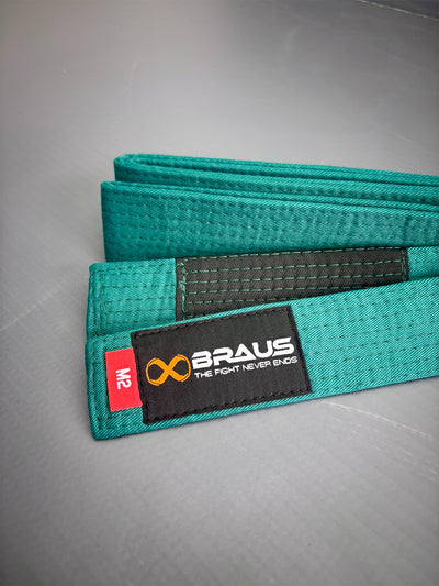 Green martial arts belt with Braus brand label on a gray background