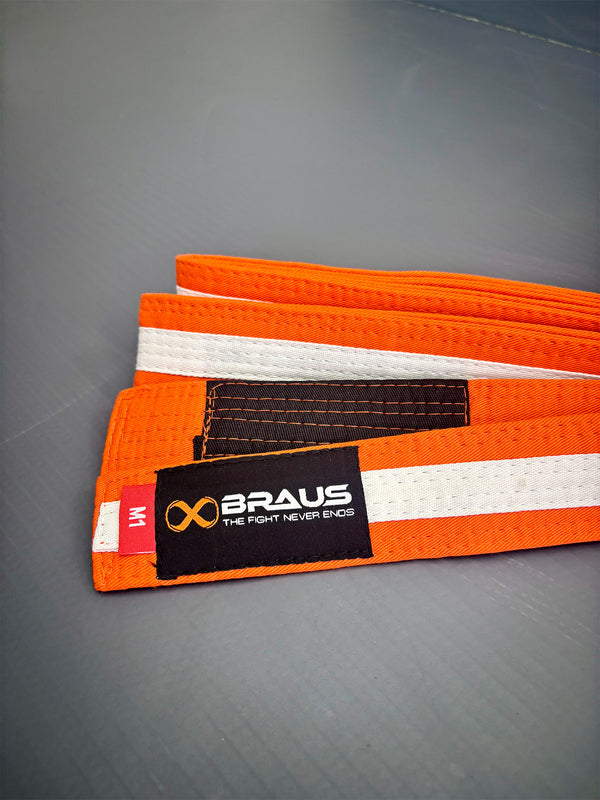 Orange/White martial arts belt with Braus logo on a gray background