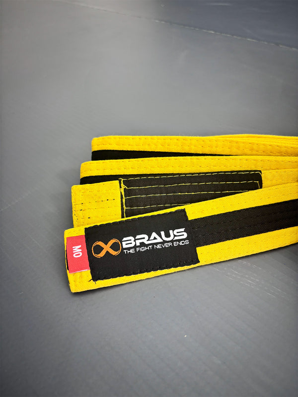 Yellow/Black martial arts belt with black strap and Braus logo on a gray background