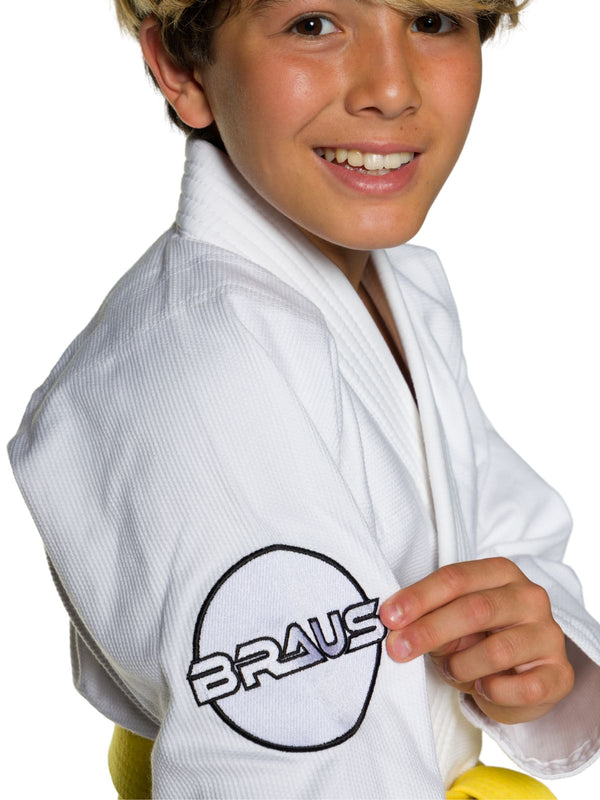 Child wearing a white martial arts gi with Braus logo on a white background