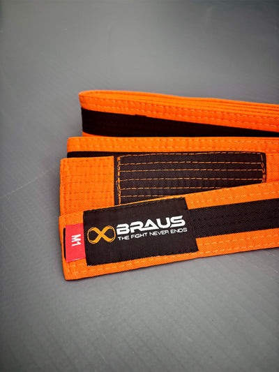 Orange/Black martial arts belt with Braus logo on a gray background