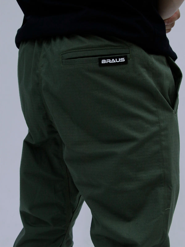 army green pants with a brand logo on the pocket against a gray background