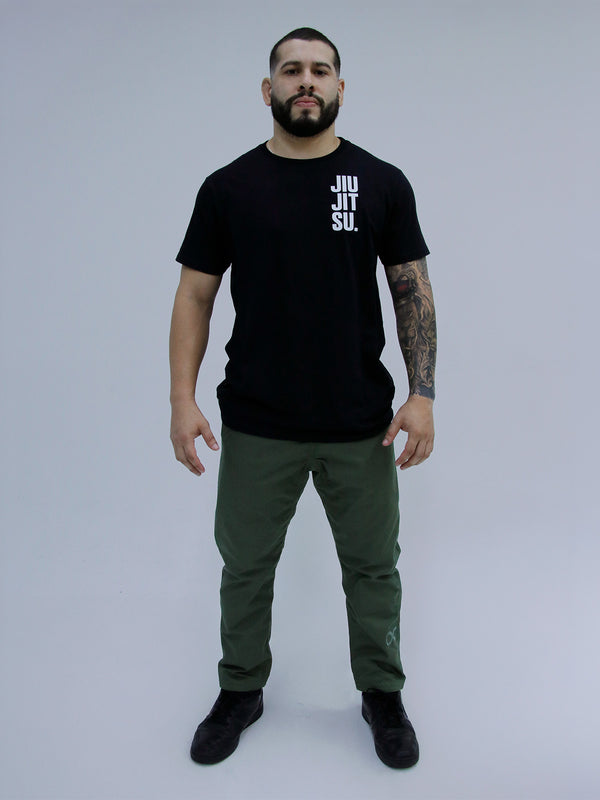 Man wearing a black 'Jiu Jitsu' t-shirt and army green pants on a gray background