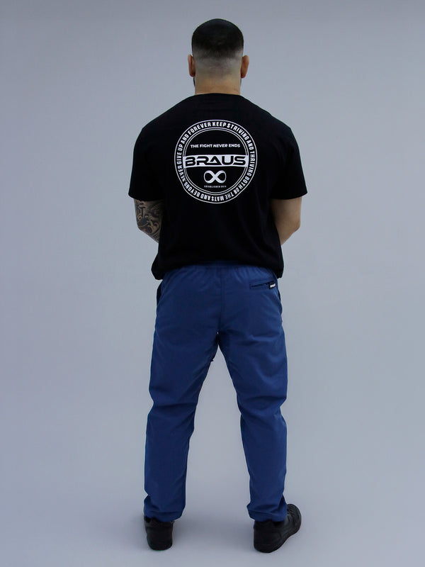 Person wearing a black t-shirt with a logo and Mid Blue Color pants on a gray background